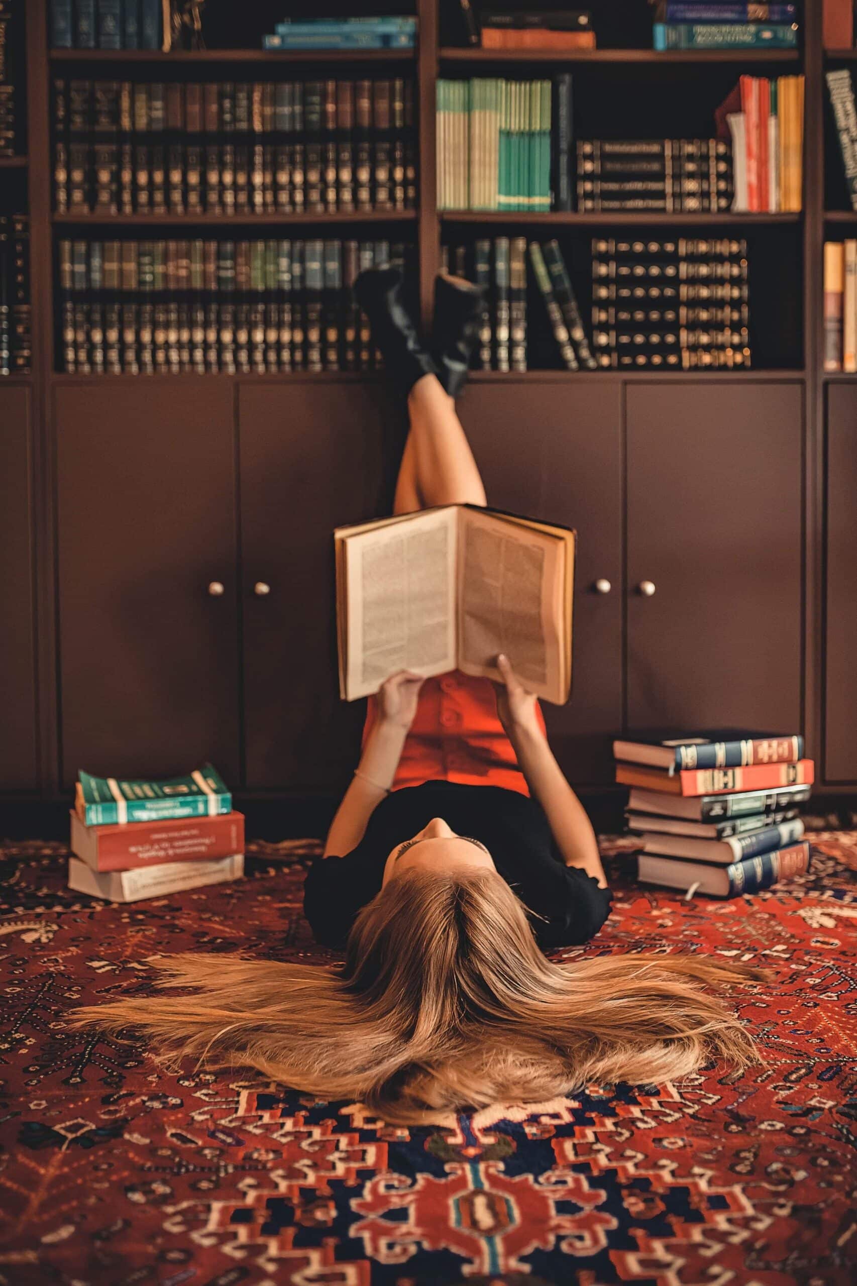 Woman lying on area rug reading books 2899918